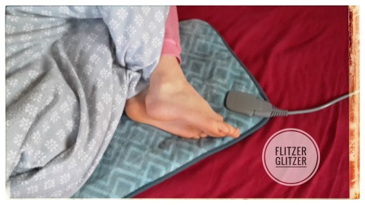 Kleine Füßchen auf elektrischem Wärmekissen.