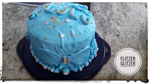 Eine über und über mit hellblauem Fondant überzogene und reichlich verzierte Torte.