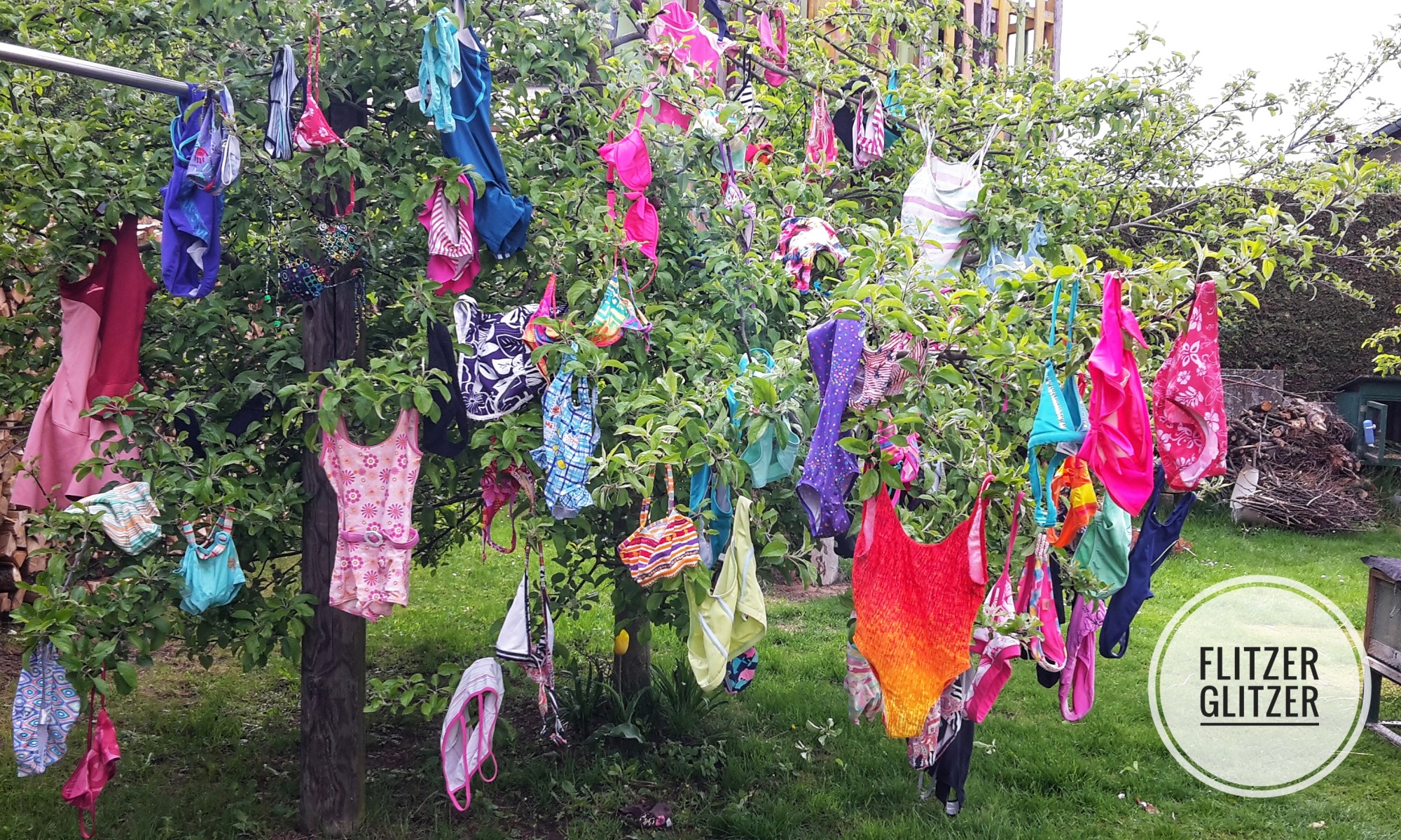 Wie Ostereier hängen die bunten Badeanzüge und Bikinis im Apfelbaum.