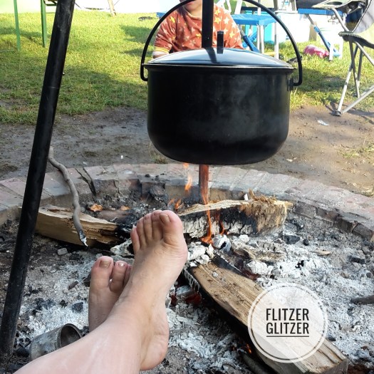 Lagerfeuer mit Kessel an Dreibein baumelnd.